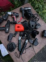 Overview of various cordless power tools, battery chargers, and battery packs arranged on a table outdoors.