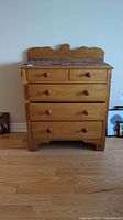 Front view of antique pine 5-drawer dresser showing two small top drawers and three larger bottom drawers with wooden knob handles and drawer liners.