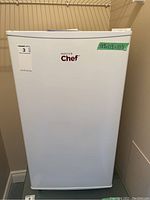 Front view of the white Master Chef fridge with sticker showing dimensions and brand logo.