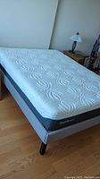 Assembled queen bed showing grey upholstered frame and white Tempur-Pedic mattress