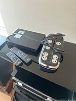 LG Blu-ray player with two remotes and a Woods power bar on black surface