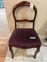 Front view of wooden chair showing upholstered seat and carved detail on backrest