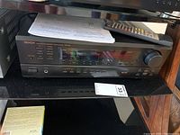 Front view of Denon DRA-395 stereo receiver with remote control and manual on top.