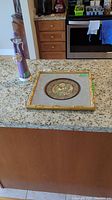 Photo of the figurine and framed embroidered art panel together on countertop.