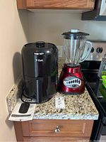 T-fal Easy Fry Compact air fryer next to Oster 12-speed blender on countertop with the T-fal manual visible.