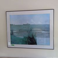 Front view of large framed landscape print hanging on wall, showing signature and scene.