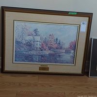 Full view of framed print leaning against wall with hardwood floor