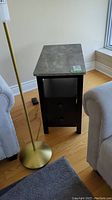 Front view of one side table showing concrete-look top, open shelf and drawers
