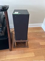 Front view of one Paradigm speaker on a wooden stand on hardwood floor