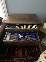 Wooden table with both drawers open showing blue felt liners and cutlery inside