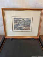 Full view of the framed print showing the wooden frame and visible matting around the print.