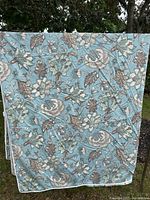 Full view of the duvet cover with floral patterned side facing out, hanging outdoors. Shows overall condition and design.