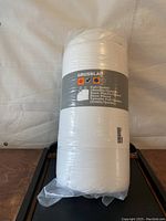Full view of the white rolled duvet in sealed plastic packaging with label showing size and warmth information.