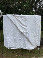 White king size duvet cover with button closure hanging outside showing terry cloth-like texture and size.