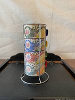 Stack of four colorful stackable espresso cups in metal stand, showing front design and colors.