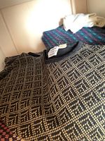 Close-up of knit sweaters with geometric patterns in neutral colors stacked on a shelf