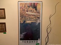 Framed poster on wall showing a detailed aerial view of Toronto city by Kim Lafaye