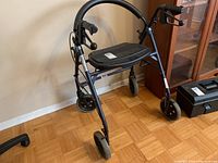 Front angled view of Dana Douglas rollator walker showing seat, front wheels, and frame details