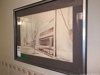 Framed watercolour painting showing an architectural modern building scene with leafless trees in the foreground, matted and framed in black wooden frame with visible marks.