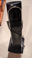Front view of black tower-style heater with mesh front and control panel on top.