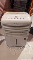 Full view of white Danby humidifier showing front air vents and water level indicator with cord coiled at base.