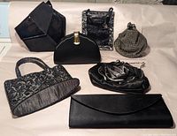 Full lot of 7 black evening handbags and clutches shown together on a light background.
