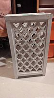 Photo of folded white wooden bifold gate with geometric cut-out pattern on panels, showing thickness and overall condition