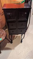Full view of the small wooden cupboard with eight drawers and metal legs showing overall size and shape.