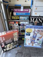 Stack of anatomy model kit boxes including The Visible Woman, The Visible Man, The Visible Head, Dimensional Man, Human Anatomy Male and an anatomy chart.