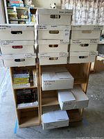 Overall view of two small wooden bookcases holding multiple labeled white cardboard boxes filled with books.