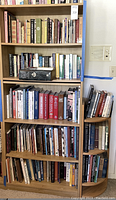 Full view of the laminate bookshelf filled with books, showing adjustable shelving and wood finish.
