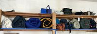 Shelves with rolled sleeping bags in various colors and fishing rod with reel on top shelf