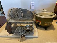 Metal Rival food slicer next to Robeson slow cooker on a white base