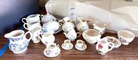 Overview of creamers, sugar bowls, teapot, cups, and saucers on table.