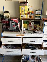Full view of the garden tools and supplies on and inside wooden drawers including boxed Craftsman blower/vac, Optimum sprayer box, Thompson's water seal can, various garden chemicals and gloves.