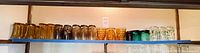 Full shelf view showing assorted glasses in amber, green, clear with prints and brown.
