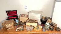 Full overview of assorted decorative jewelry boxes and keepsakes arranged on wooden surface including various shapes and materials