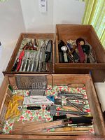 Overview of wooden drawers holding the utensils including Henckels steak knives, cheese spreaders, graters, skewers, and other kitchen tools