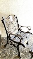 Outdoor decorative iron and wood chair showing detailed floral and leaf iron backrest with curved iron armrests and wooden slats