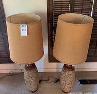 Pair of table lamps with wood and cork bases and burlap shades, showing front view and some visible cork damage.