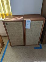 Front view of both speakers showing wood cabinets and beige cloth grills