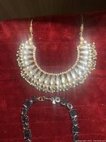 Photo of large ornate East Asian style necklace with tear-drop shaped clear elements and pearl-like beads along with a black gem-link necklace