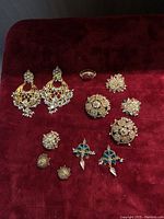 Full collection displayed on red velvet with earrings, brooches, pins, and ring