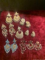 Full view of the vintage East Asian jewelry collection on red velvet, showing earrings and rings arranged in two rows.