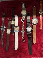 Full view of all 9 watches laid out on red background showing variety of band materials and dial styles.