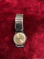 Front view of vintage Timex automatic wrist watch on red fabric showing dial and metal expandable band