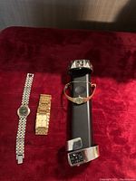 Four women's wristwatches displayed on a red velvet surface, showing different styles including bracelet and cuff bands.