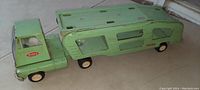 Full side view of the green metal Tonka truck hauler showing the cab, trailer, and wheels.