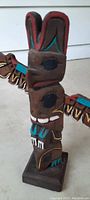 Mini carved totem pole showing face details and wing extension with colorful paint