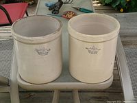 Two stoneware crocks side by side on a table, showing full shape and size.
